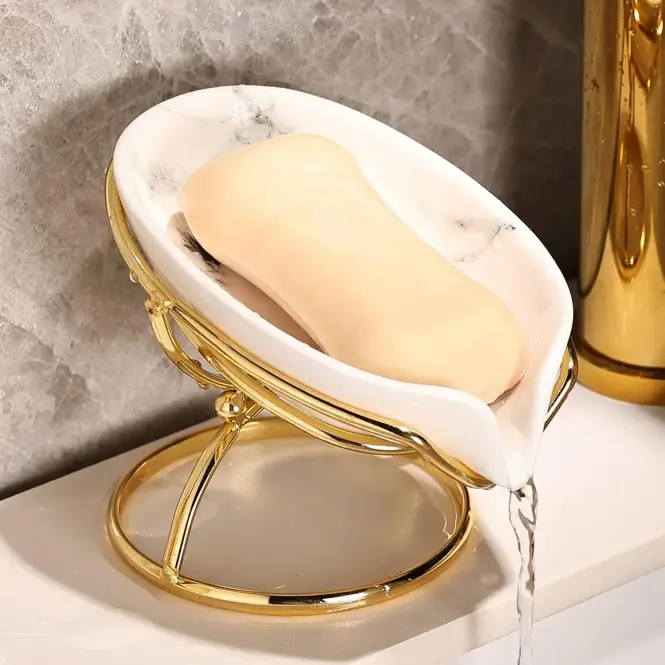 Leaf ceramic soap dish holding a cream soap bar on a stone sink edge with water droplets and soft window light